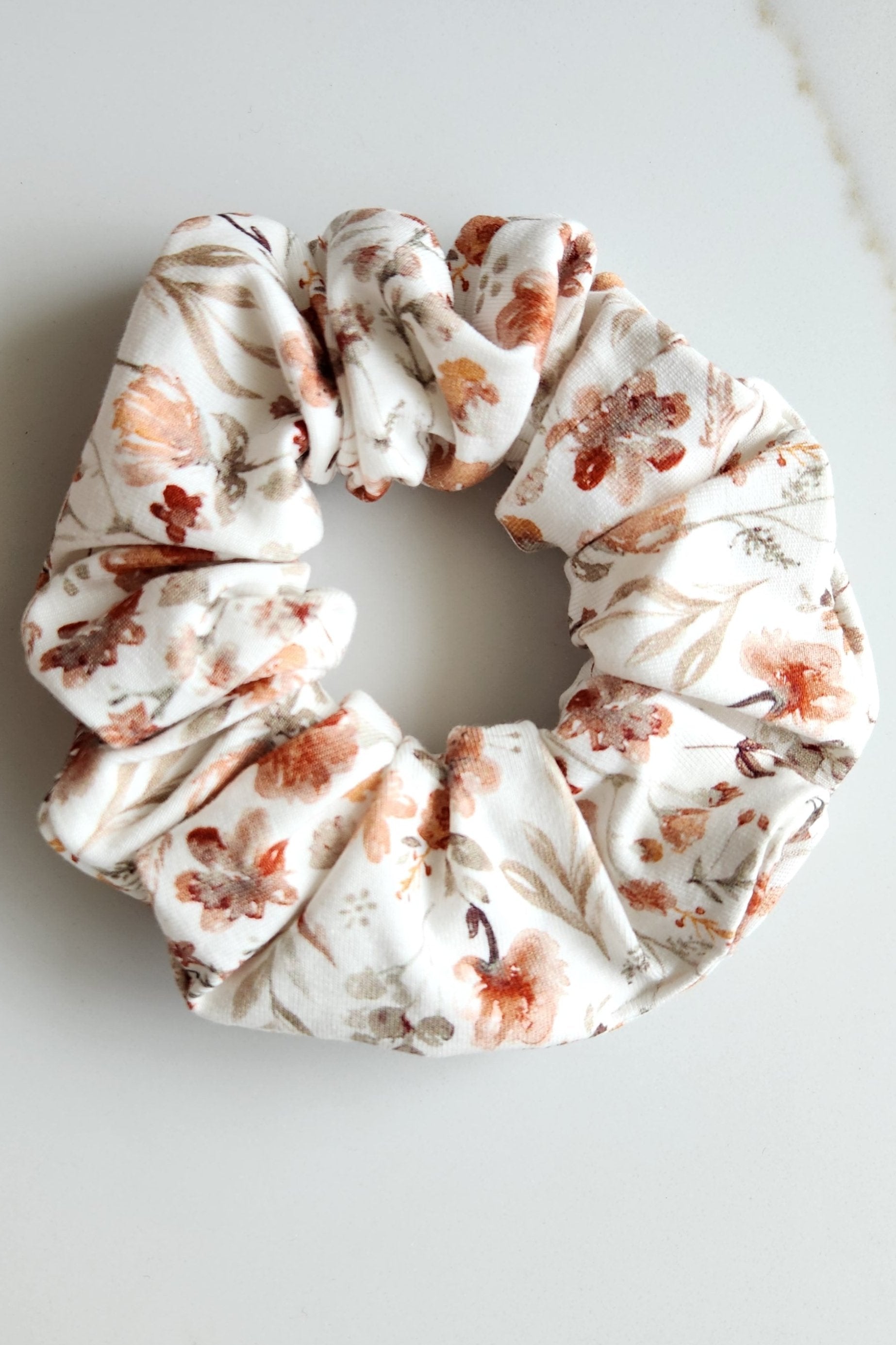 White cotton jersey scrunchie with autumn florals in oranges and rust colours.